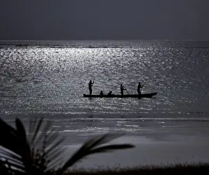 Kenya Coast Prints: Three men pole a dugout canoe by moonlight in shallow water along Diani Beach