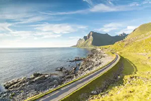 The midnight sun shines on the asphalt road between sea and rocky mountains Vikten