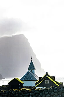 Climate Collection: Misty sky over the traditional church of Vidareidi ovelooking a fjord, Vidoy Island, Faroe Islands