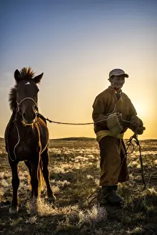 Gobi Desert Prints: Mongolian shepherd wearing traditional dress in steppe of Gobi desert with his hourse