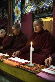 Monks during evening candle light prayer in Lhodrak Kharchu monastery, Jakar
