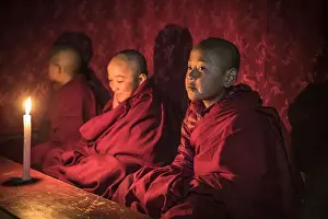 Monks during evening candle light prayer in Lhodrak Kharchu monastery, Jakar