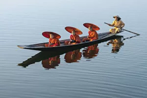 Images Dated 23rd April 2020: Three monks in orange robes with bowls for alms giving and a leg-rowing fisherman commute