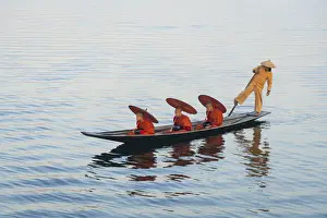 Commuters Prints: Three monks in orange robes with bowls for alms giving and a leg-rowing fisherman commute