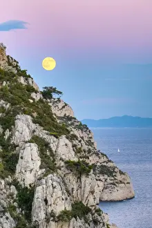 Full moon rising over ocean and Mediterranean landscape at Calanque de Sugiton after