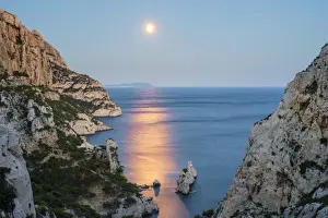 Full moon rising over ocean and Mediterranean landscape and Calanque de Sugiton at dusk