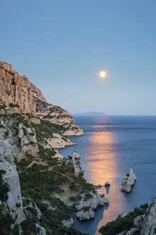 Full moon rising over ocean and Mediterranean landscape and Calanque de Sugiton at dusk