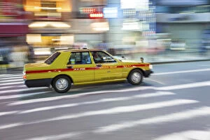 Motion blurred yellow taxi cab on pedestrian crossing, Tokyo, Japan