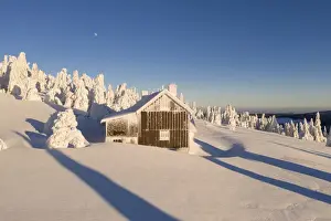 Mountain cottage in deep snow-covered winter landscape at Fichtelberg at sunset