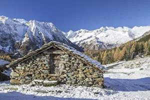 A mountain hut surrounded by snow capped peaks and colorful woods in autumn at Alp Entova A mountain hut surrounded by snow capped peaks and colorful woods in autumn at Alp Entova