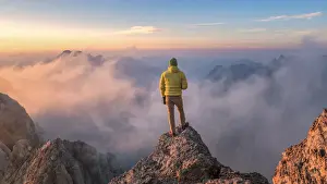 Trento Prints: mountaineer admires the landscape at sunrise from a rock spur near Punta Penia, Marmolada