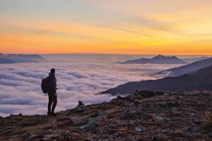 A Mountaineer enjoying the sunrise with the foggy Inn Valley and Kellerjoch mountain in the background