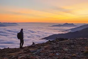Inntal Prints: A Mountaineer enjoying the sunrise with the foggy Inn Valley and Kellerjoch mountain in the background