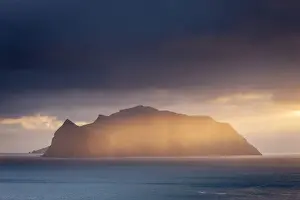 Mykines Prints: The mountainous island of Mykines, illuminated by a golden ray of evening sunshine