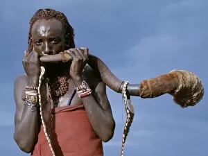 Maasai Tribe Collection: A Msai warrior blows a trumpet fashioned from the