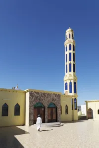 Oman Prints: A mullah walks into a colourful mosque for the call to prayer, Nizwa, Ad Dakhiliyah