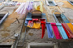 Multicolored Prints: Multicolored laundry hangs in front of an old facade, Venice, Veneto, Italy