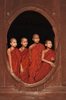 Boys Prints: Myanmar, Burma, Nyaungshwe. Young novice monks standing at a wooden oval window