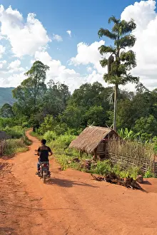 Motor Bike Prints: Myanmar, Burma, Shan, Keng Tung, a motorcyclist rides through a village near Keng Tung