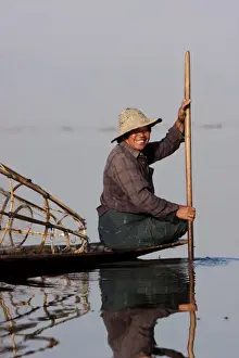 Burmese Man Prints: Myanmar, Inle Lake. Intha fisherman gently paddling his boat across Inle Lake, Myanmar