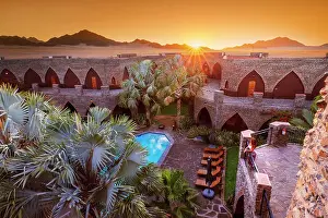 Namibia, a tourist watching the sunset in a luxury hotel in the Namib Naukluft National Park with the sun setting on the Namib desert dunes MR