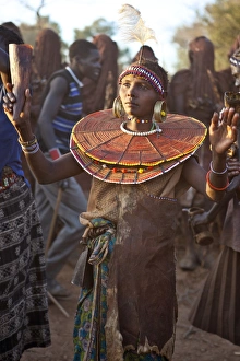 During a Ngetunogh ceremony, the mother of a Pokot initiate sings and dances holding high the cowhorn container she used to smear fat over the masks of her son and other boys as