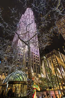 Rockefeller Center Prints: Night low angle view of trees wrapped with Christmas lights and Rockefeller Center