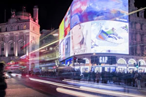 A night shot of light trails in front of the advertising hoardings in Piccadilly Circus