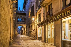 Barrio Gotico Prints: Night view of Carrer del Bisbe street with the picturesque Pont del Bisbe bridge