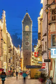 Sterzing Prints: Night view of the main street and Zwolferturm medieval tower decorated with Christmas lights