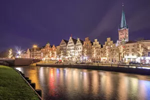 Night view of typical houses and the cathedral reflected in river Trave Lubeck Schleswig