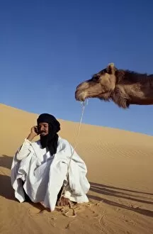 Sahara Desert Gallery: A nomad sits in the desert and talks on his mobile phone