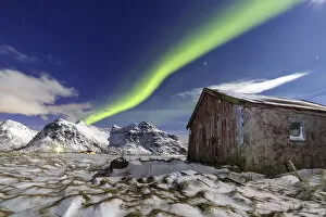 Northern Lights over an abandoned log cabin surrounded by snow and ice