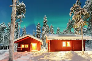 Chalet Prints: Northern Lights over illuminated log cabins set among frozen trees in a snowy forest
