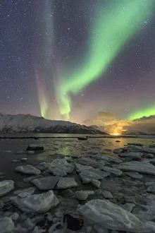 The Northern Lights illuminates the icy landscape in Svensby Lyngen Alps TromsaAA¸ The Northern Lights illuminates the icy landscape in Svensby Lyngen Alps TromsaAA¸