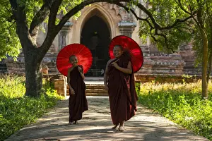 Two People Prints: Two novice Buddhist monks with red umbrellas walking away from temple, Bagan