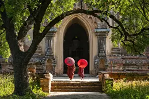 Two People Prints: Two novice Buddhist monks with red umbrellas walking to temple, Bagan, Mandalay Region