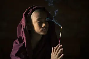 Head And Shoulders Prints: Novice monk holding a lit incense stick while praying inside a temple, UNESCO, Bagan