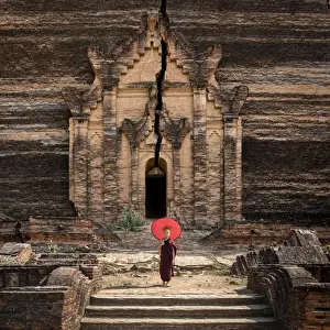 Novice monk standing in front of the unfinished Pahtodawgyi pagoda known for a crack