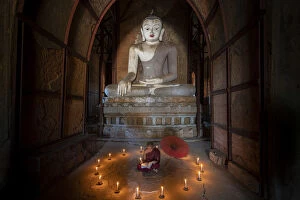 Umbrella Gallery: Novice monk studying inside a temple under big Buddha statue, UNESCO, Bagan