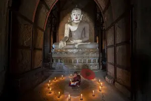 Sitting Prints: Novice monk studying inside a temple under big Buddha statue, UNESCO, Bagan