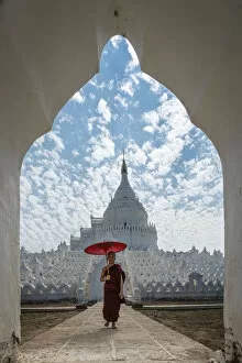 Novice monk walking with an umbrella at Hsinbyume pagoda, Mingun, Mandalay