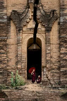 Two novice monks at the entrance to the unfinished Pahtodawgyi pagoda known for a crack