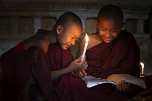 Two novice monks reading a book inside a temple in candle light, UNESCO, Bagan