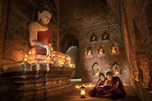 Two novice monks studying inside a temple under big Buddha statue, UNESCO, Bagan