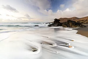 Ocean waves breaking on sand beach Playa de la Solapa at sunset, Fuerteventura