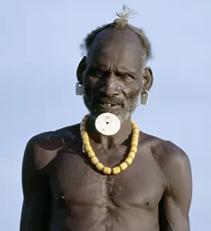 An old Dassanech man wearing a traditional lip ornament and earrings
