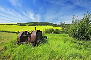 Tractor Prints: Old farm equipment (tractor) and canola crop on farmland Baljennie Saskatchewan, Canada