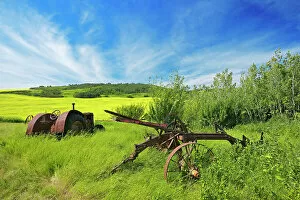 Agribusiness Gallery: Old farm equipment (tractor and cultivator) and canola crop on farmland Baljennie Saskatchewan