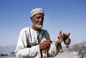 Oman Collection: An old goatherd spins wool at his village on the rim